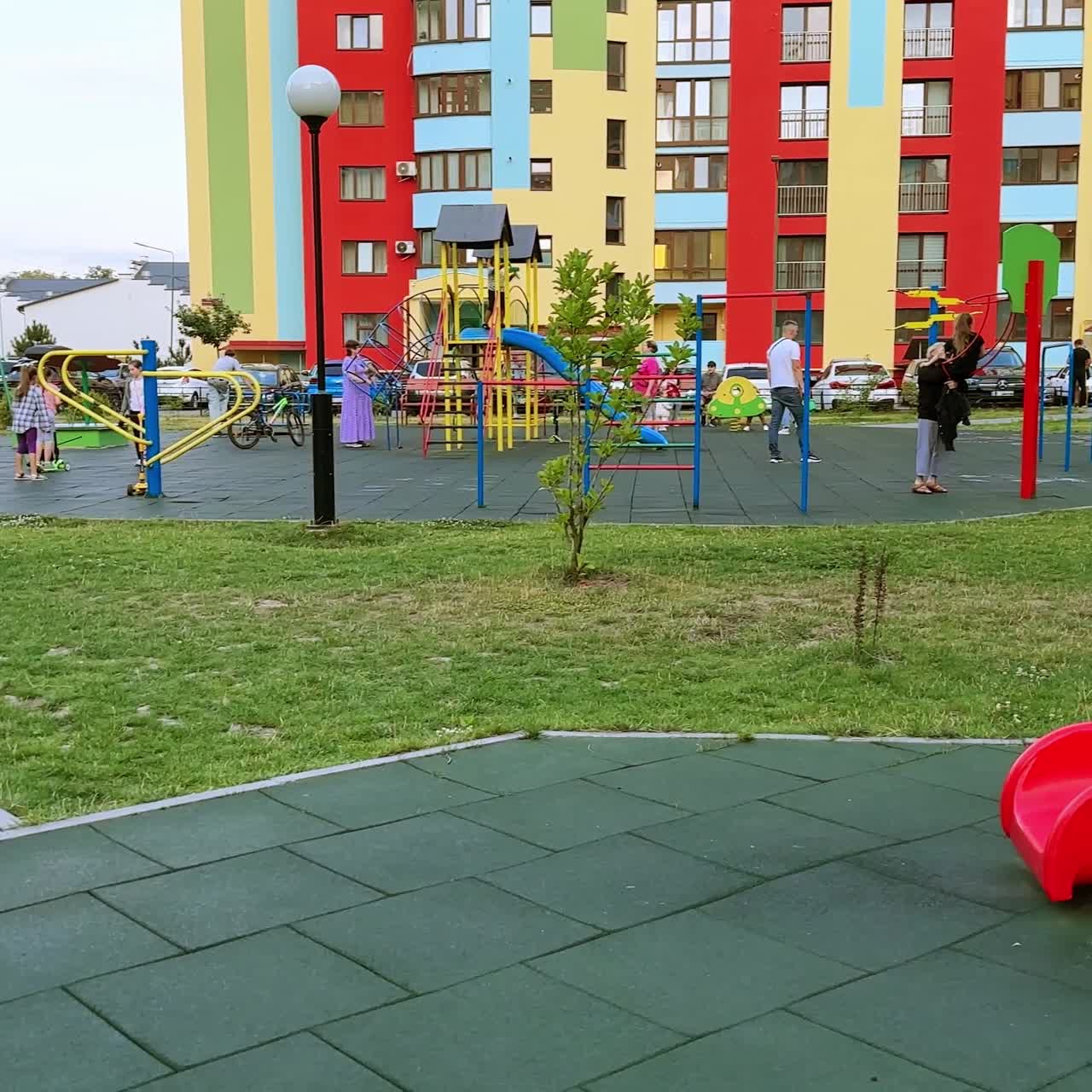 Lächelndes Kind klettert die Rutschleiter hoch. Der glückliche kleine Junge rutscht hinunter und rennt zum Spielplatz.