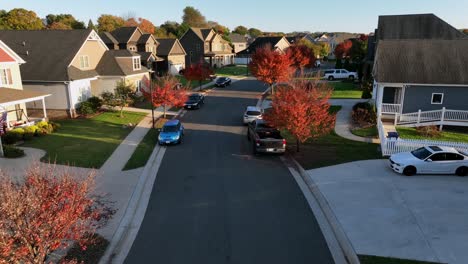 ups delivery truck on street of new developed american housing area. beautiful golden sunrise in luxury neighborhood with colorful trees in fall season. aerial approaching shot. flyover shot.