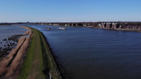 Commercial-Barges-Sails-On-Serene-Canal-Of-River-Noord-Near-Hendrik-Ido-Ambacht,-South-Holland,-Netherlands