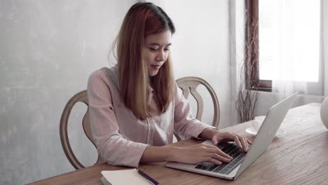 young asian woman is working on her laptop from home office