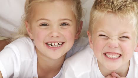 close up of smiling siblings in bed