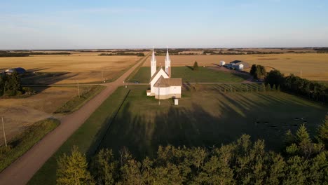 aerial flying forward shot of roman catholic church in north american prairie during sunset