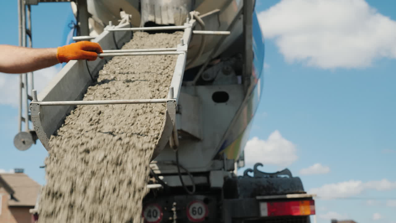 작업자가 콘크리트가 흐르는 낙하산을 지시하는 기초를 붓는 작업