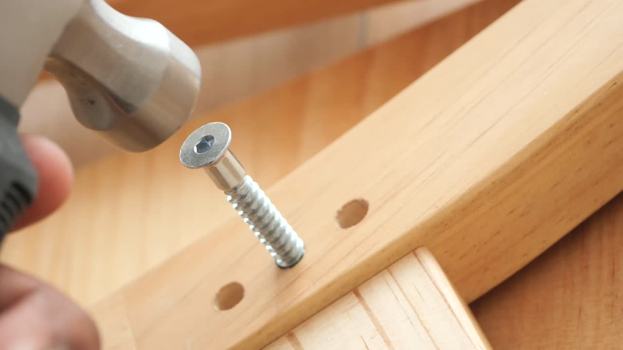 Hammering a screw into a wooden chair