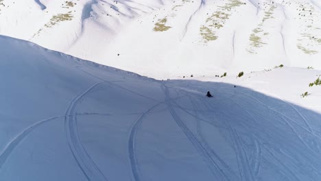 Malerischer-Blick-Auf-Schnelles-Schneemobil,-Das-Sich-Einer-Drohne-Auf-Einem-Weißen-Schneebedeckten-Berg-Nähert,-Mit-Schneemaschinenspurlinien-Im-Schatten-An-Einem-Hellen-Sonnigen-Tag,-Akoura,-Libanon,-Rückwärtsantenne