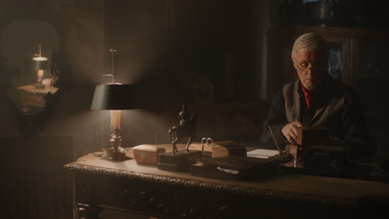 Older passionate man evaluates an old watch in his office at night