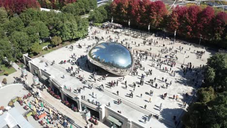 bean statue in chicago, illinois with people walking around and drone video pulling out