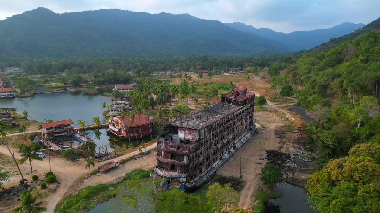 Abandoned resort showing decaying buildings, surrounded by palm trees and a lake, in Koh Chang, Thailand. Spectacular aerial view flight overflight flyover drone
