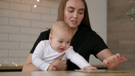 Concepto-De-Familia,-Tecnología-Y-Maternidad:-Feliz-Y-Sonriente-Madre-Joven-Con-Un-Bebé-Y-Una-Tableta-En-Casa