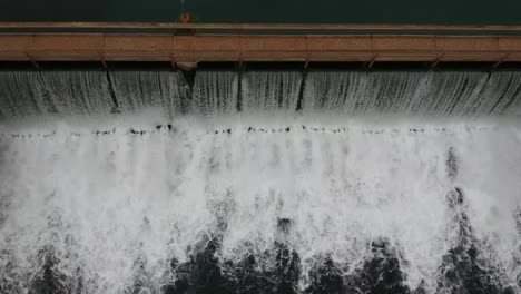 top down drone angle of water rushing thru a dam