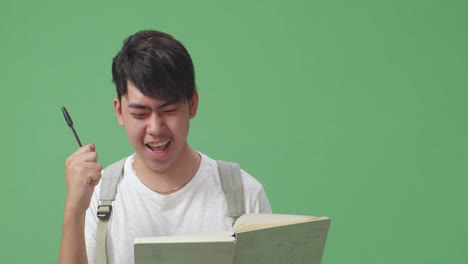 close up of asian man student note on book and celebrating in green screen studio