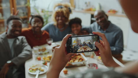 chica fotografiando a la familia con el teléfono en la cena de vacaciones en casa
