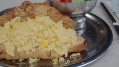 scrambled eggs in a croissant on a plate