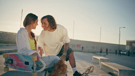 dos patinadores saliendo en el estadio en verano. una pareja romántica besándose en un banco de primer plano.