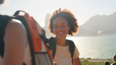 group of female friends with backpacks helping each other on hike in countryside on coastal path