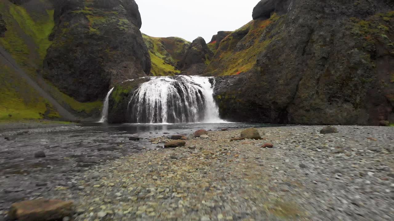 río que fluye con guijarros y la cascada de stjornarfoss, islandia