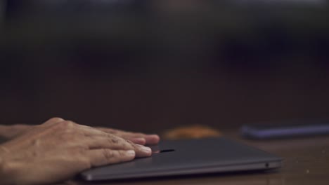 toma cinematográfica de manos escribiendo un mensaje en una computadora portátil y luego cerrando la computadora
