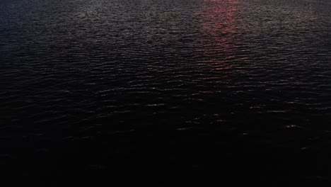 flying over a calm ocean, tilting up and revealing islands and a cloudy sunrise