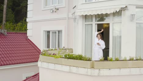 woman on balcony of pink house