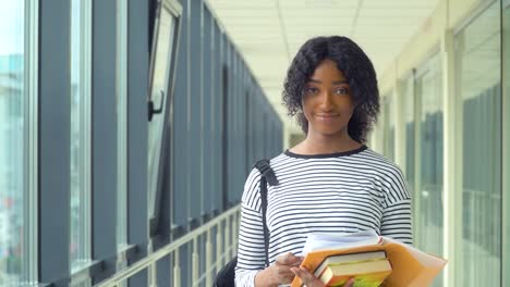 african american woman student with a books in the university. new modern fully functional education facility. concept of online education