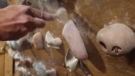 Close-up-view-of-a-climber-brushing-the-chalk-of-a-climbing-hold-at-the-gym