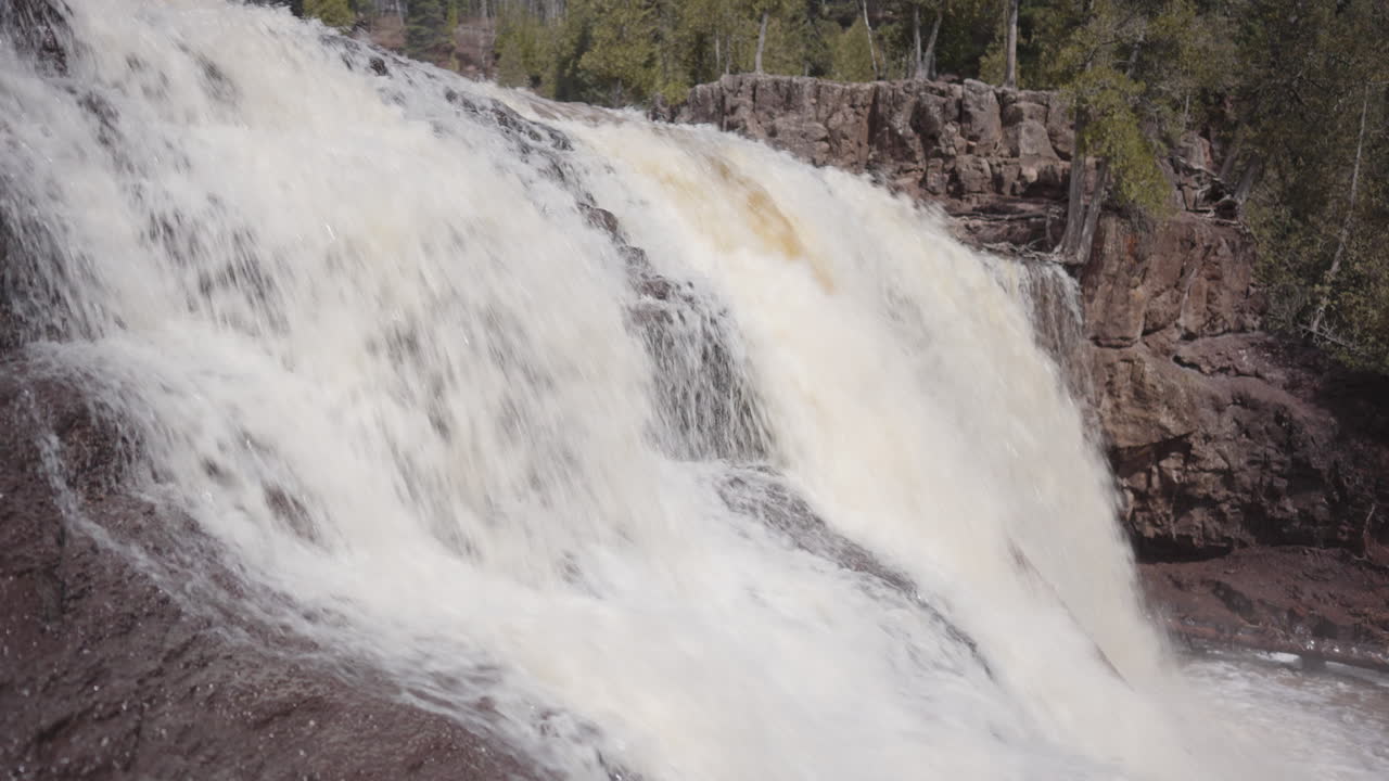 Thundering Falls Cascading Over Rocky Cliff into River