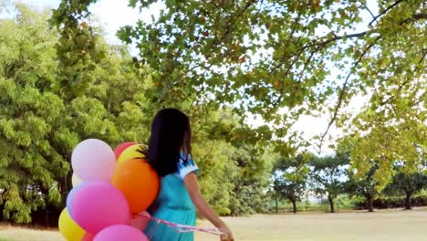 smiling girl playing with balloons in park