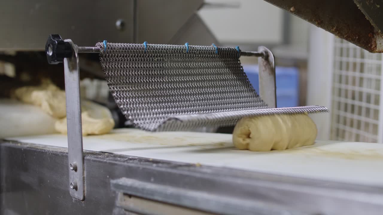 Raw Fresh Bread Dough Being Rolled By Chain Mail On Conveyor Belt. Low Angle