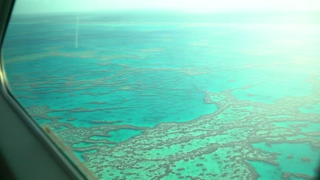 stunning turquoise waters at great barrier reef during sunrise, seaplane window view