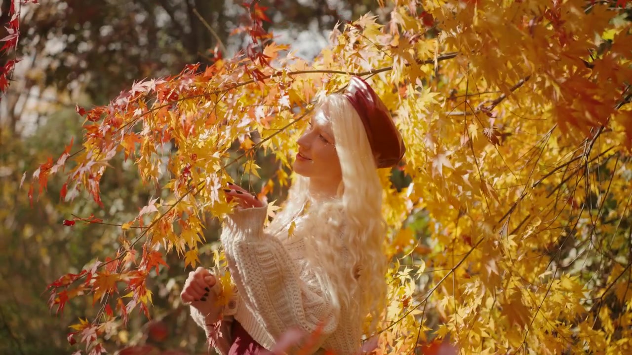 Donna europea che ammira le foglie di acero giapponese con una luce brillante intorno a Forest Park, circondata dall'autunno arancione e rosso mentre il vento soffia, al rallentatore.