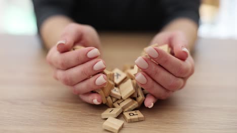 hands interacting with wooden scrabble letter tiles