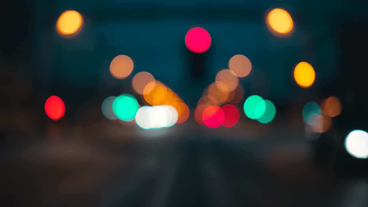 Displaying traffic lights fluctuating with passing headlights at intersection under streetlights