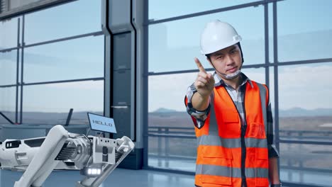 ingeniero asiático con casco de seguridad desaprueba sin señal del dedo índice mientras está de pie en una fábrica de alta tecnología, analizando el concepto de máquina robótica