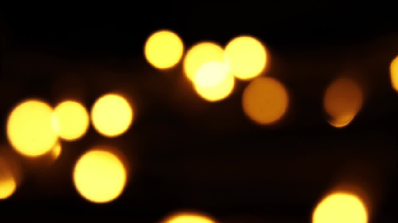 Abstract bokeh background in motion. shining, blurred golden particles, lights. bright bokeh from garlands on dark background. New year or Christmas festive backdrop