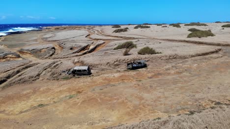 Aerial-drone-shot-4k-upward-and-forward-movement---Car-tracks-off-road-amongst-rolling-grassland-with-the-pacific-on-the-horizon