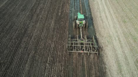 un tractor labra un campo de granja en wisconsin después de que un esparcidor de estiércol haya esparcido estiércol líquido en el campo de la granja