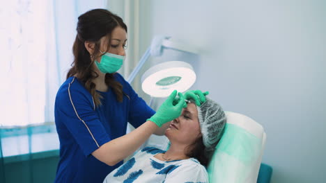 beautician does injections in spots on woman forehead