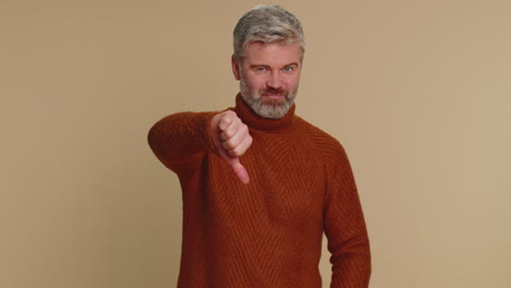 upset senior man guy in sweater showing thumbs down sign gesture, disapproval, dissatisfied dislike