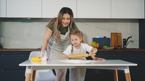 Madre-E-Hija-Sonríen-En-La-Cocina,-Mientras