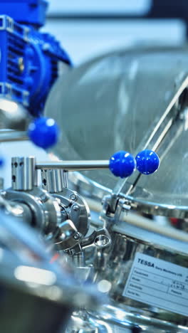 modern factory of dairy products indoors. worker opens metal mixer inside the milk plant. cheese production process. contemporary equipment for making fresh cheese. close-up. vertical video