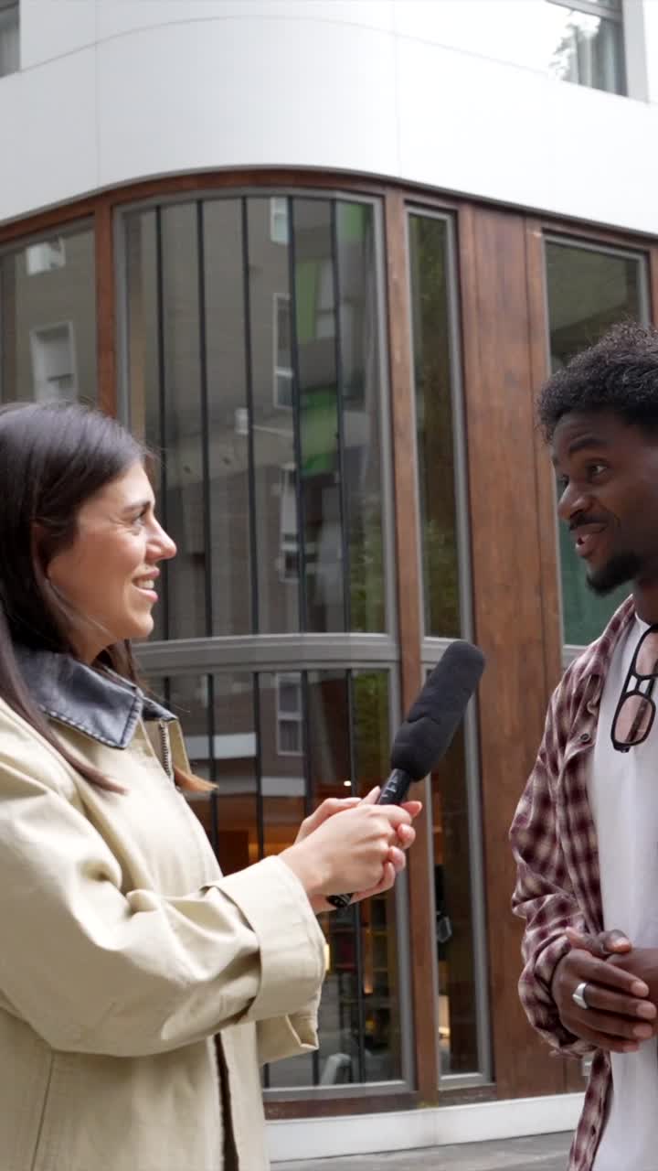 Woman Interviews Man with Microphone on City Street