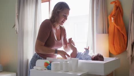 video de una madre caucásica feliz cambiando a un bebé recién nacido