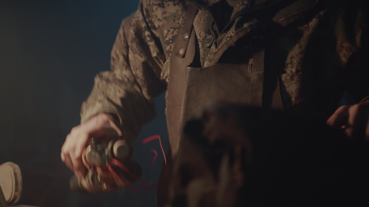 A bombmaker assembles a bomb in his workshop at night
