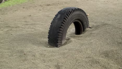 old car wheel buried in sand. parallel sliding view.