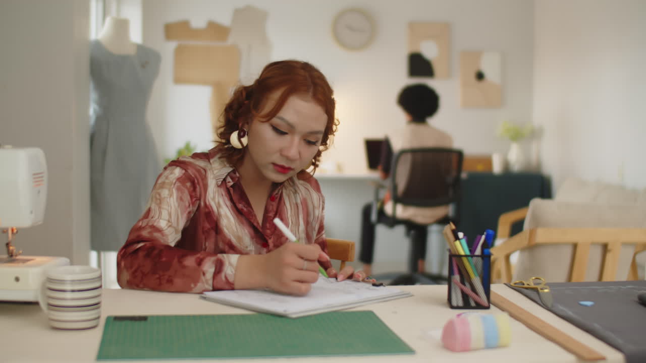 Seamstress Drawing Sketch of Dress in Sewing Atelier