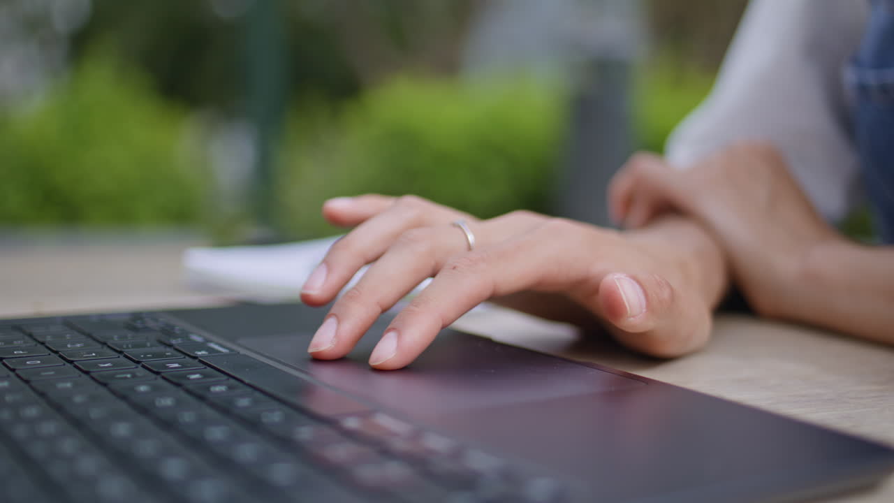 Girl hands using touchpad laptop at street cafe closeup. Unknown woman fingers