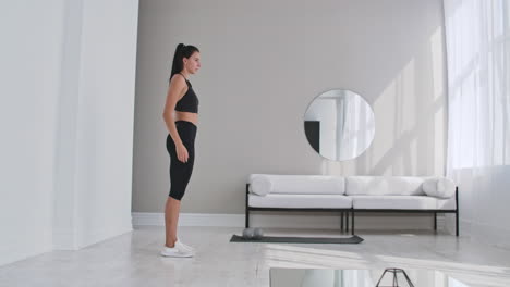 beautiful fit girl doing home workout performing lateral lunges in a sitting room