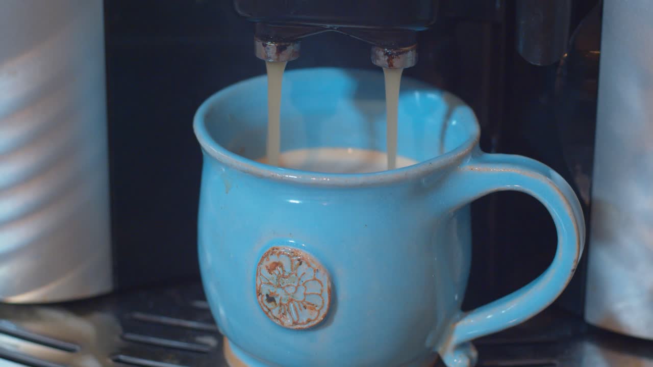 café espresso que va de la máquina de frijoles a tazas a una taza azul hecha a mano