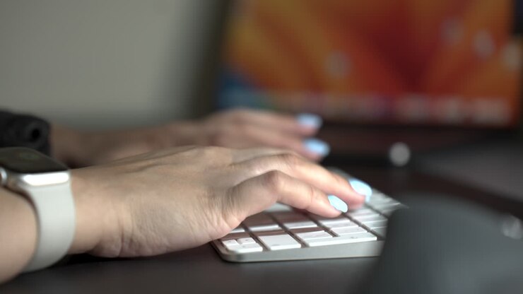 Persona che digita su una tastiera bianca per computer, vista laterale