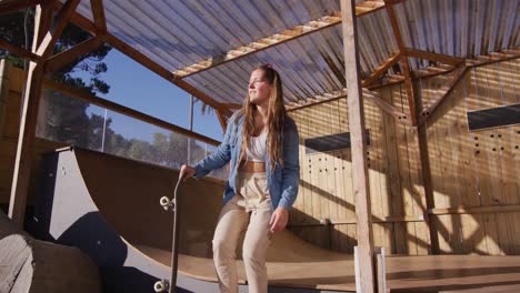 video of happy caucasian female skateboarder training in skate park